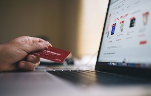 hand with credit card resting on laptop showing shopping website